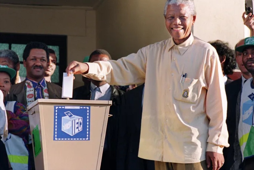 ANC president Nelson Mandela smiles on April 27, 1994, as he casts his first vote at the polling station at John Langalibalele Dube’s Ohlange High School in Inanda, near Durban, in South Africa’s first democratic general elections. On his right is former minister Jeff Radebe.